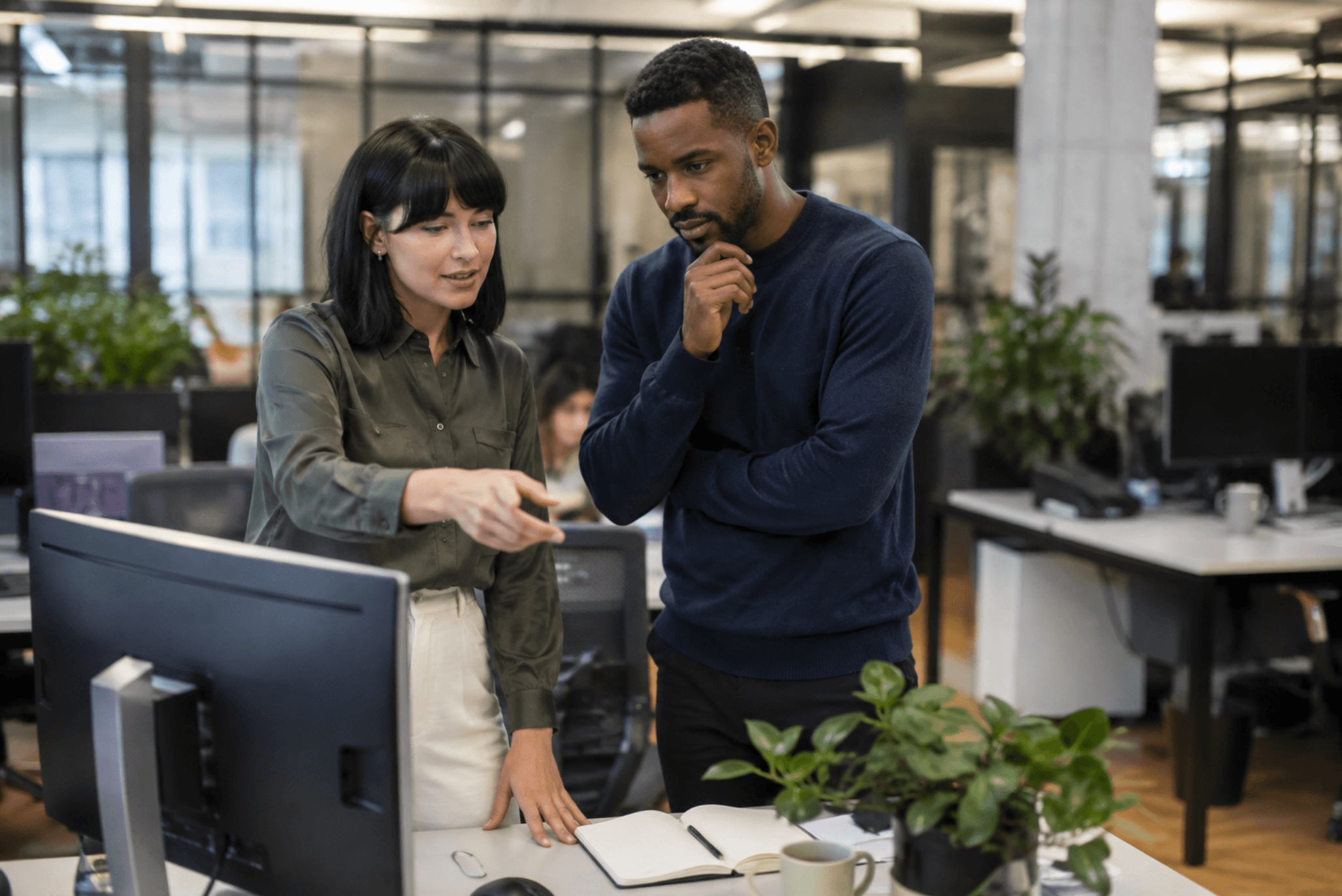 Two employees reviewing workplace training content on a computer in a modern office.