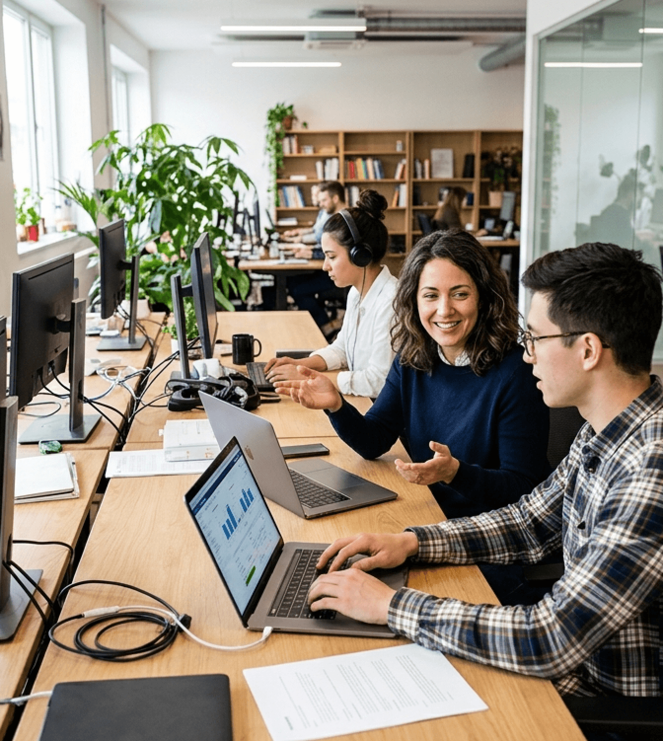 Employees collaborating on laptops in a modern office while creating digital training content.