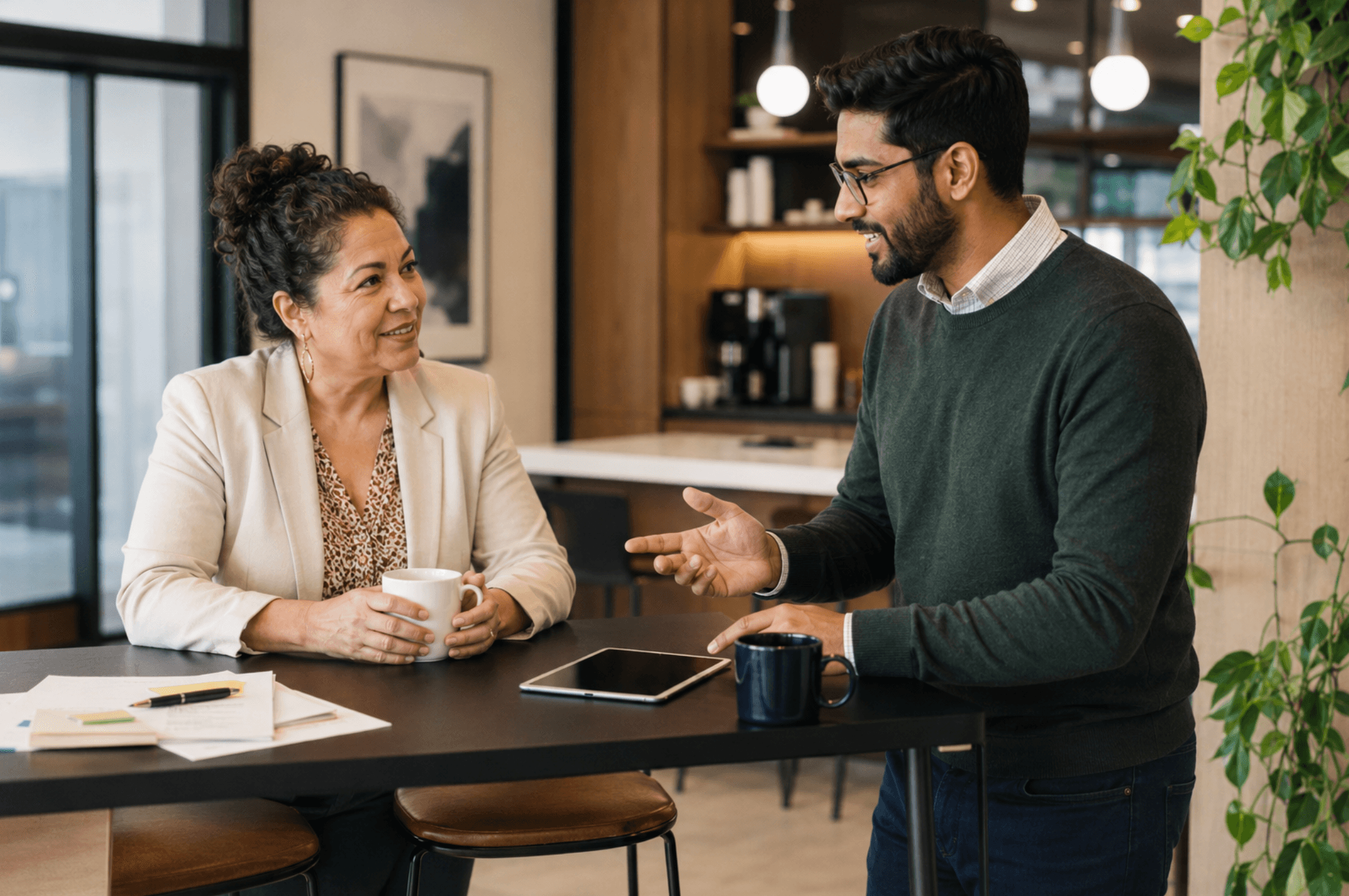 Two employees discussing workplace learning and sharing ideas in a modern office.